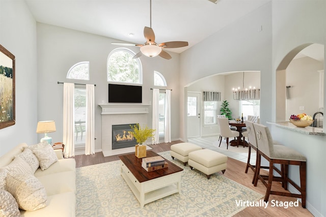 living room with ceiling fan with notable chandelier, plenty of natural light, hardwood / wood-style flooring, and a tile fireplace