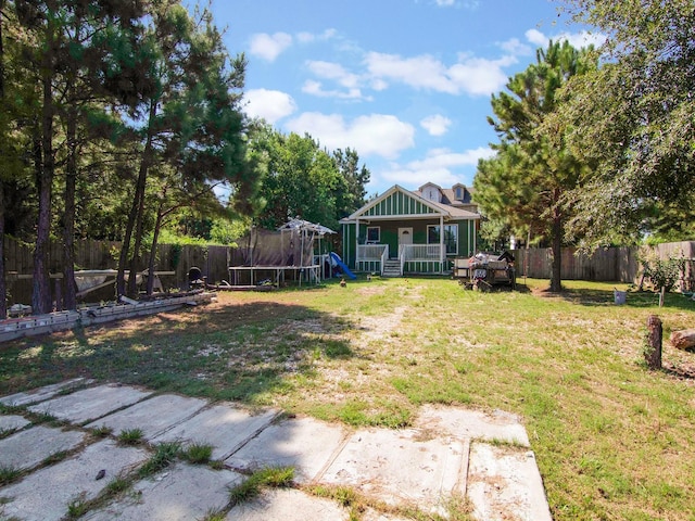view of yard with a trampoline, a fenced backyard, and a playground