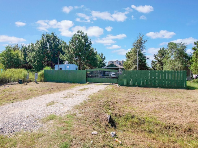 view of yard featuring driveway, a gate, and fence