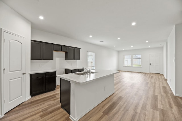 kitchen featuring a kitchen island with sink, recessed lighting, light wood-style flooring, and a sink