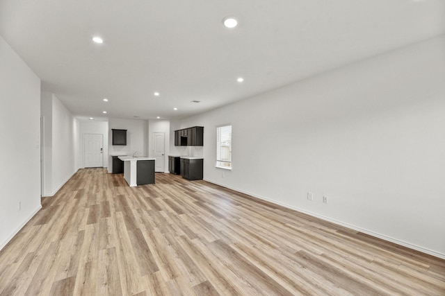 unfurnished living room featuring light wood finished floors, recessed lighting, and baseboards