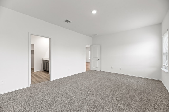 unfurnished bedroom featuring light carpet, ensuite bath, and a spacious closet