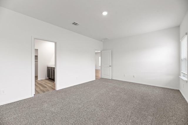 unfurnished bedroom featuring recessed lighting, ensuite bath, visible vents, baseboards, and light colored carpet