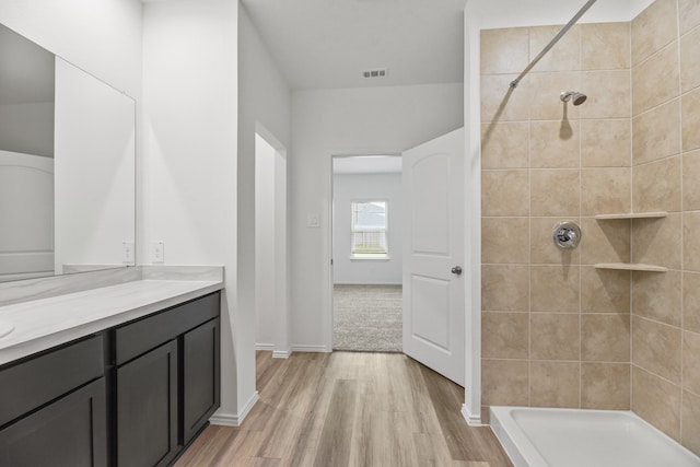 bathroom featuring hardwood / wood-style floors, vanity, and a tile shower