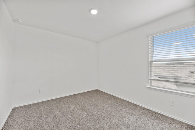 carpeted empty room featuring baseboards
