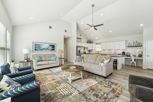 living room featuring ceiling fan, light wood-type flooring, sink, and high vaulted ceiling