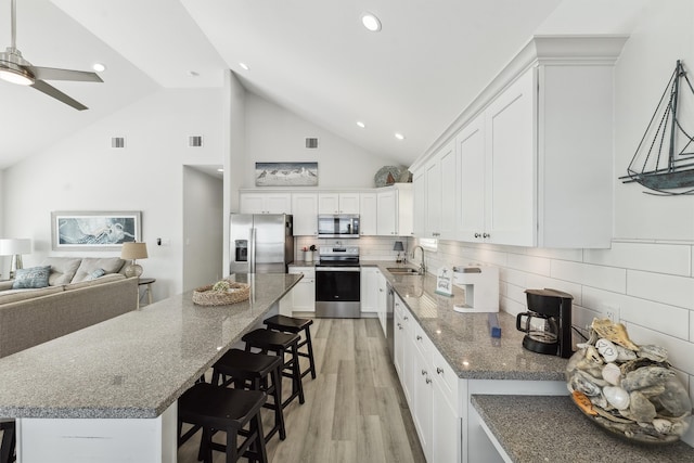 kitchen featuring light wood-type flooring, stainless steel appliances, sink, high vaulted ceiling, and white cabinets