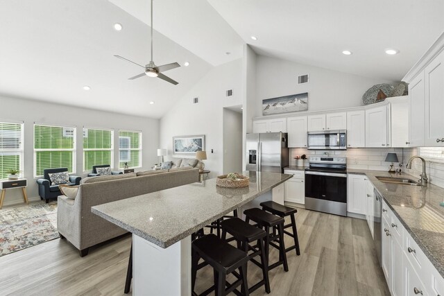 kitchen featuring white cabinets, a kitchen breakfast bar, appliances with stainless steel finishes, and light hardwood / wood-style flooring