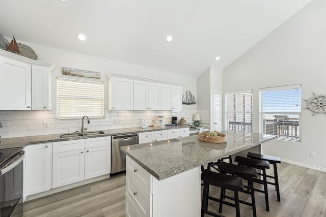 kitchen with dark stone counters, sink, a kitchen island, and stainless steel dishwasher