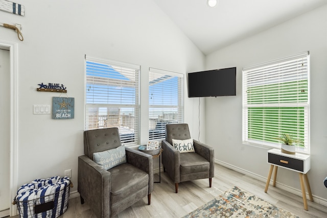 living area with hardwood / wood-style flooring, a healthy amount of sunlight, and vaulted ceiling