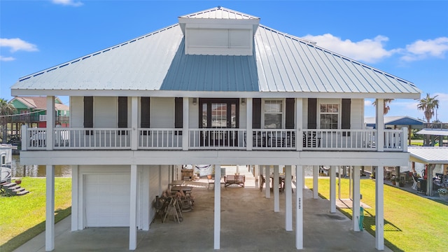 rear view of property featuring a yard, a garage, and covered porch