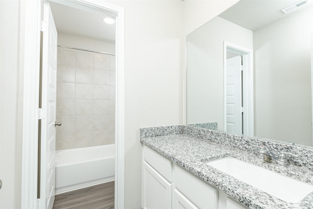 bathroom featuring wood-type flooring, vanity, and tiled shower / bath