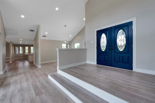 foyer featuring light hardwood / wood-style floors, french doors, and high vaulted ceiling