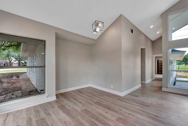 spare room featuring light hardwood / wood-style flooring and high vaulted ceiling