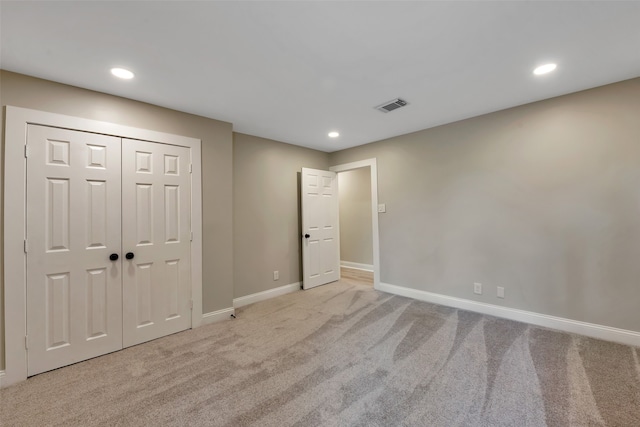 unfurnished bedroom with light carpet and a closet