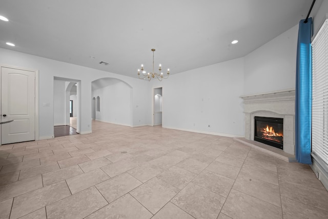 unfurnished living room featuring a premium fireplace and a chandelier