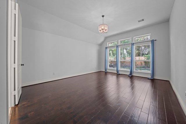 spare room featuring dark wood-type flooring, vaulted ceiling, and an inviting chandelier