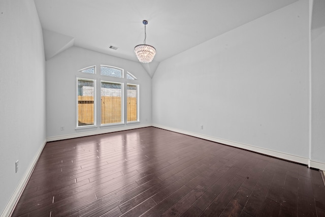 spare room featuring dark hardwood / wood-style flooring, lofted ceiling, and an inviting chandelier