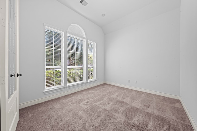 carpeted spare room featuring vaulted ceiling