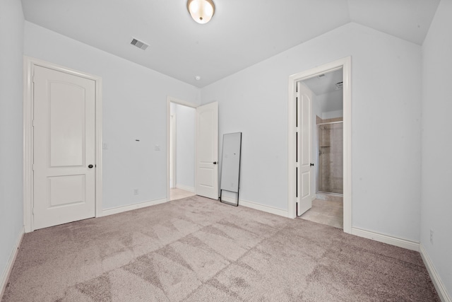 unfurnished bedroom with light carpet, ensuite bathroom, vaulted ceiling, and a closet