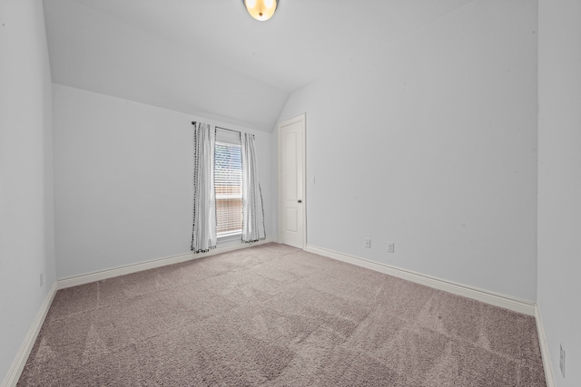 carpeted empty room with lofted ceiling