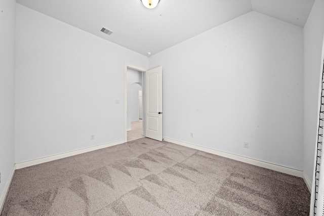 unfurnished room with light carpet and lofted ceiling