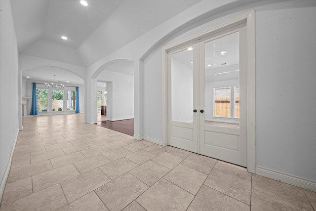 foyer with french doors, plenty of natural light, lofted ceiling, and a notable chandelier