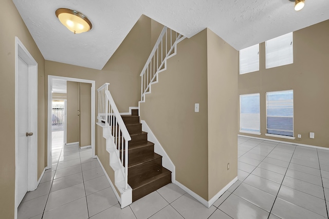 stairs with tile patterned flooring and a textured ceiling