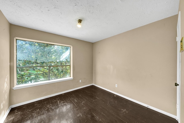 spare room with a textured ceiling and dark hardwood / wood-style floors