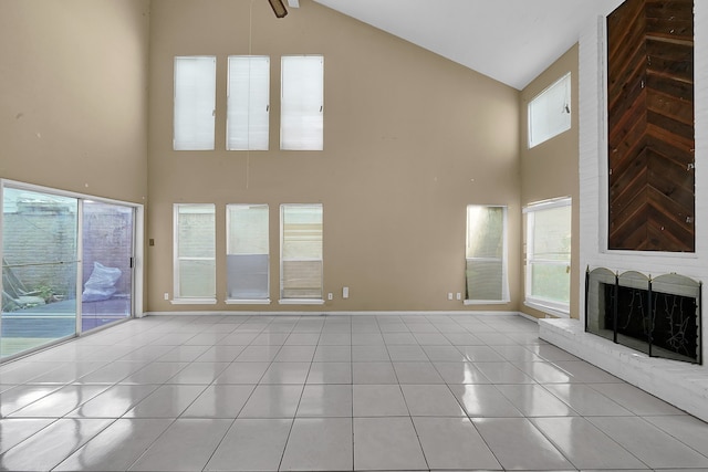 unfurnished living room with a brick fireplace, light tile patterned flooring, high vaulted ceiling, and ceiling fan