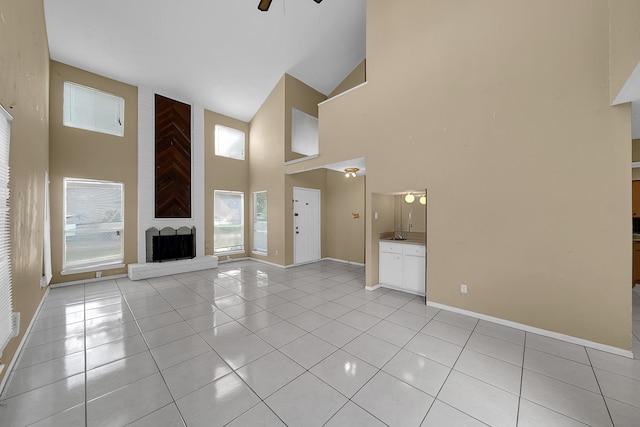 unfurnished living room featuring a towering ceiling, ceiling fan, and light tile patterned floors