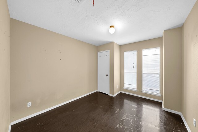 empty room with a textured ceiling and dark hardwood / wood-style flooring