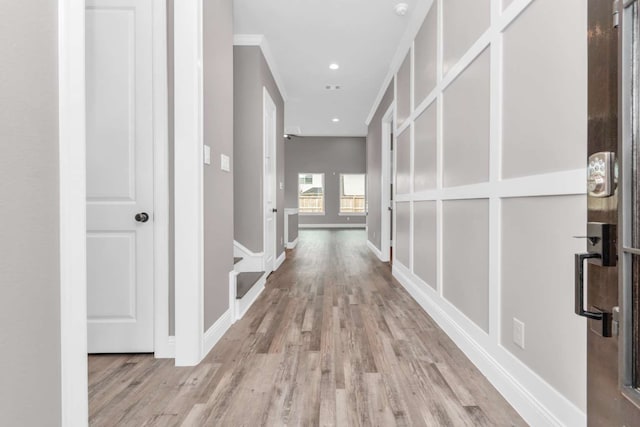 corridor with light wood-type flooring and ornamental molding