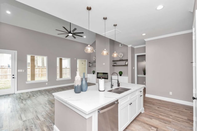 kitchen featuring white cabinets, ceiling fan, stainless steel dishwasher, a kitchen island with sink, and sink