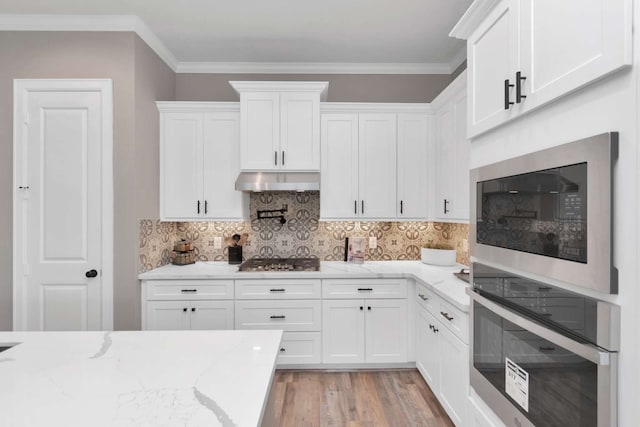 kitchen featuring light stone countertops, stainless steel appliances, white cabinets, and light wood-type flooring