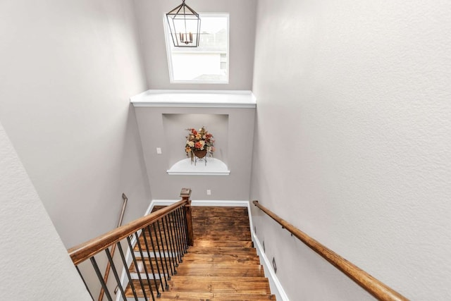 stairs with hardwood / wood-style flooring and a chandelier