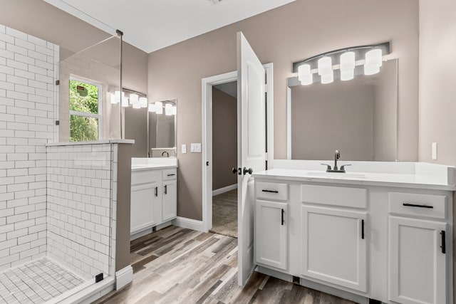 bathroom with a tile shower, vanity, and wood-type flooring