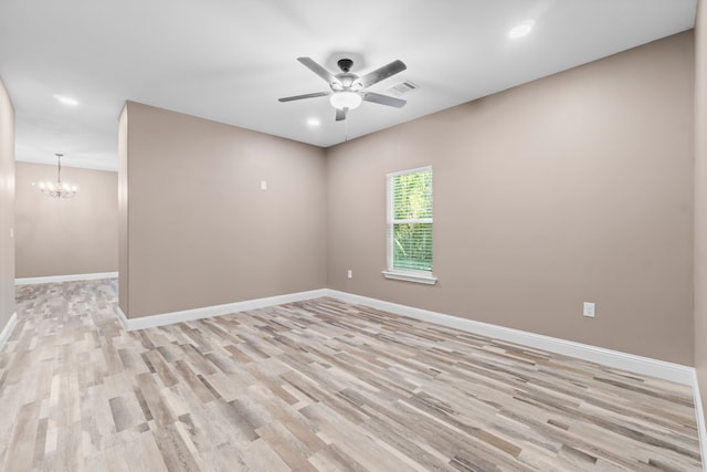 spare room with light wood-type flooring and ceiling fan with notable chandelier