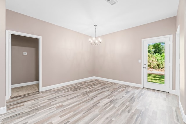 unfurnished room featuring light hardwood / wood-style flooring and a chandelier