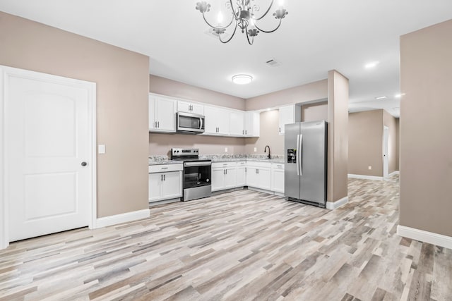 kitchen featuring appliances with stainless steel finishes, light hardwood / wood-style floors, white cabinets, sink, and a notable chandelier