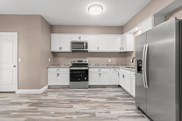 kitchen with appliances with stainless steel finishes, light hardwood / wood-style flooring, and white cabinets