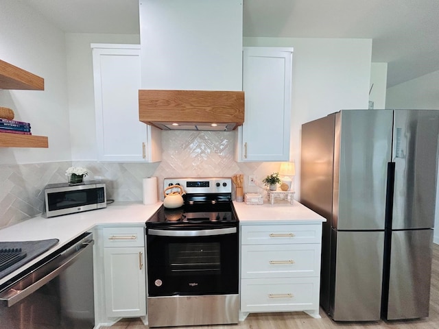 kitchen with light hardwood / wood-style floors, white cabinets, backsplash, exhaust hood, and stainless steel appliances