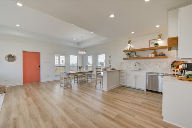 kitchen with light hardwood / wood-style flooring, white cabinetry, hanging light fixtures, and dishwasher