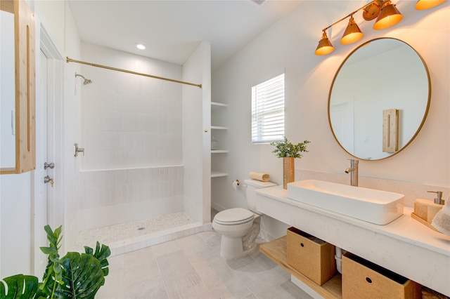 bathroom featuring a tile shower, vanity, toilet, and tile patterned floors