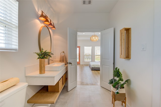 bathroom with a notable chandelier, hardwood / wood-style flooring, vanity, and toilet