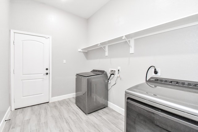 laundry area with light wood-type flooring and washing machine and clothes dryer