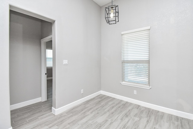 unfurnished room with a chandelier and light wood-type flooring