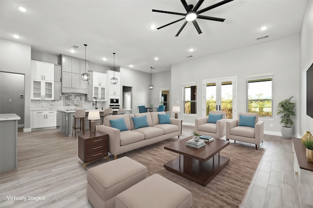 living room featuring sink, light wood-type flooring, and ceiling fan