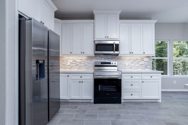 kitchen featuring decorative backsplash, stainless steel appliances, and white cabinetry