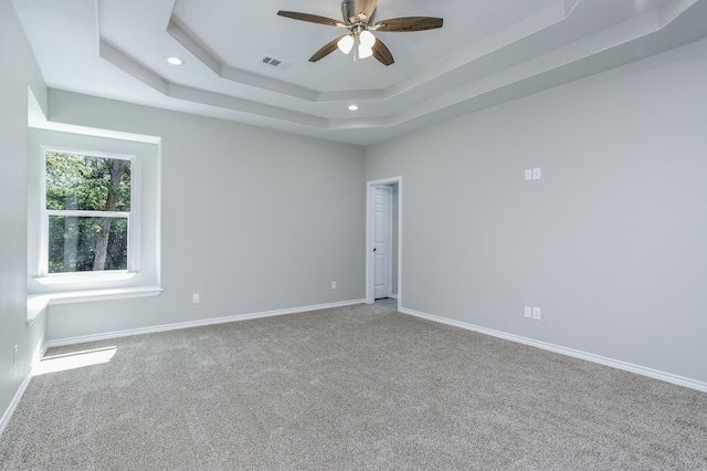 spare room featuring carpet, a tray ceiling, and ceiling fan